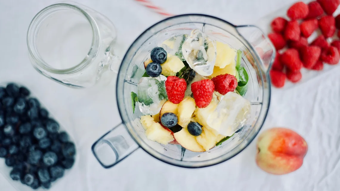 Ein Hochleistungsmixer gefüllt mit frischen Zutaten für einen Smoothie.